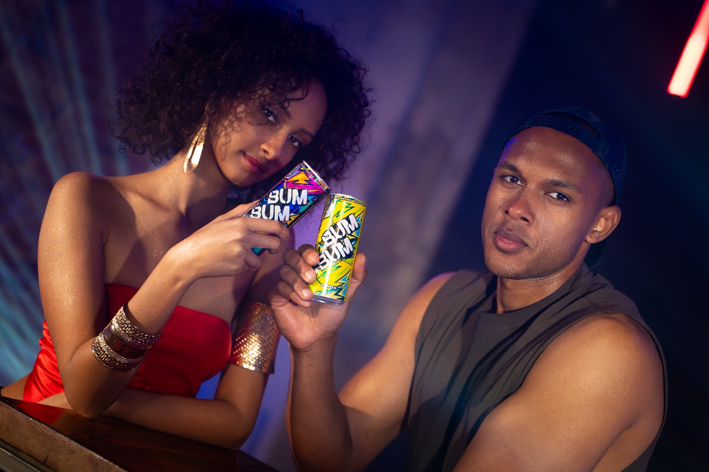 Two friends holding BUM BUM Energy Drink cans at a party